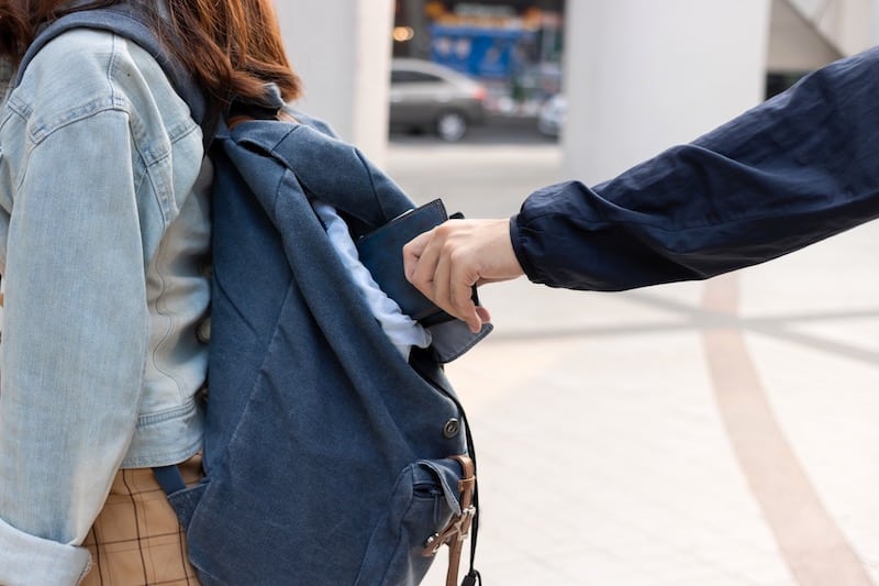 A Thief Pulling Out A Wallet From Someones Backpack