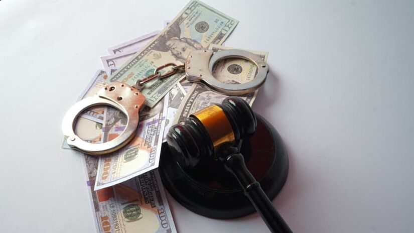 Gavel hammer, US dollar banknotes and handcuffs on white background. 