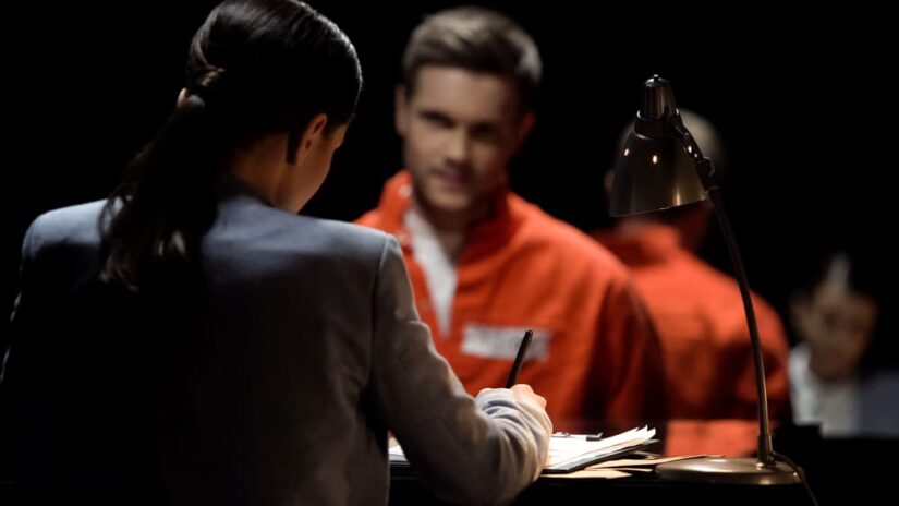 Female defense attorney writing accused prisoners statements for court.