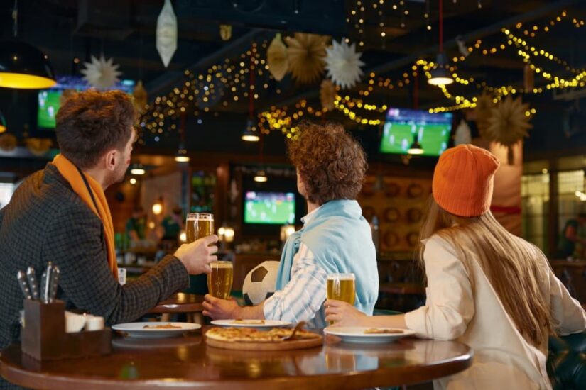 Group of friends watching football match on tv in Bar