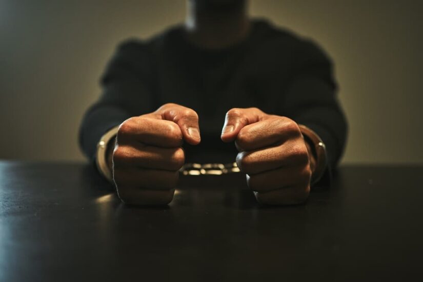 Interrogation, jail and hands of criminal in handcuffs for interview, investigation and arrested in station.